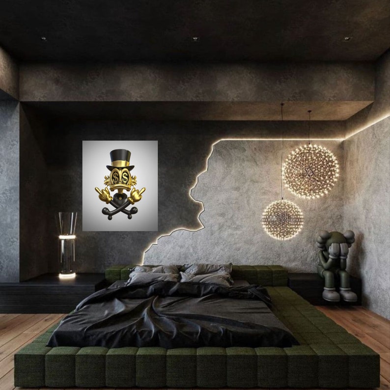 May include: A black and gold 3D sculpture of a cartoon character wearing a top hat and holding a skull and crossbones. The sculpture is hanging on a white wall in a modern bedroom with a black bed and green headboard. The room has a concrete wall with a decorative light fixture.