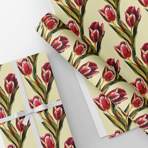 May include: Gift wrap featuring a repeating pattern of red tulips with green stems and leaves on a cream background. A wrapped gift tied with a white ribbon is shown next to rolls of the same wrapping paper.