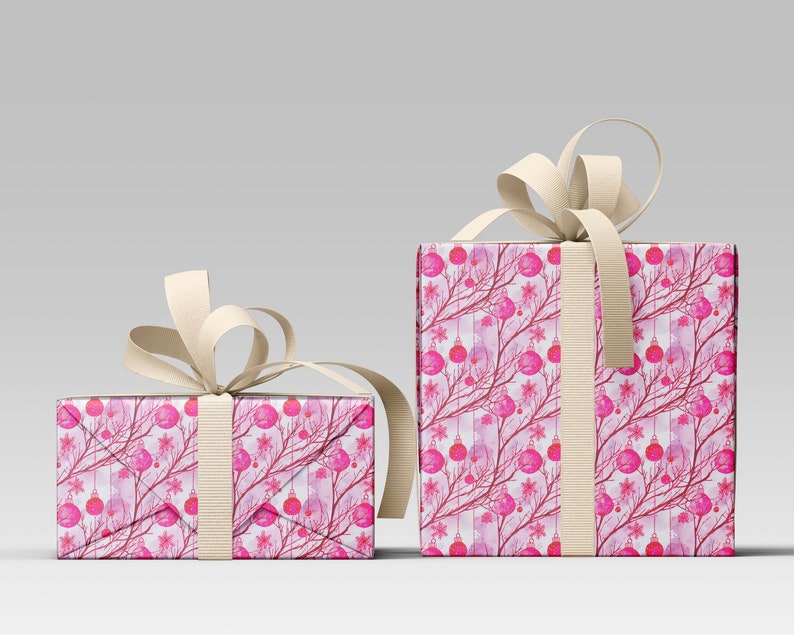 May include: Two wrapped gift boxes with a festive Christmas design. The wrapping paper features a pattern of pink ornaments, branches, and snowflakes on a white background. Each box is tied with a cream-colored ribbon.