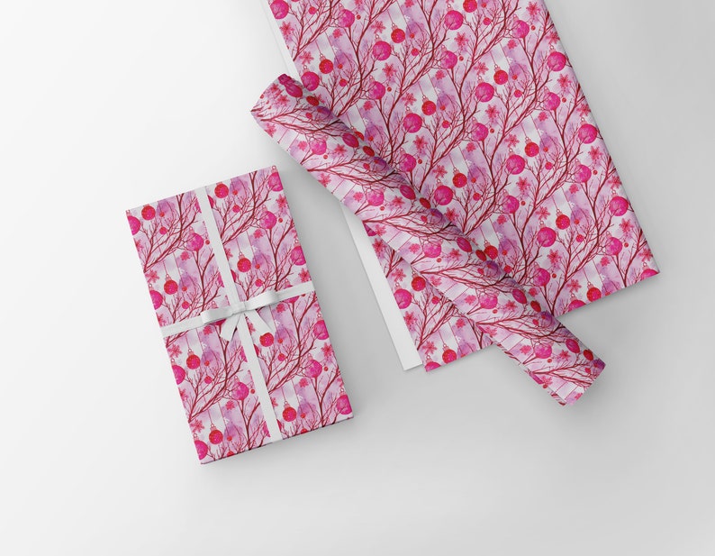 May include: Gift-wrapped box and wrapping paper featuring a watercolor design of pink orbs, branches, and floral accents on a white background. The box is tied with a white ribbon. The paper is rolled and flat.
