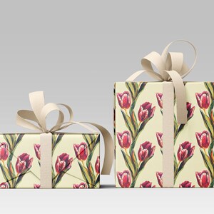 May include: Two gift boxes wrapped in floral patterned paper featuring red tulips with green leaves on a cream background. The boxes are tied with cream-colored ribbon and bows, creating a visually appealing presentation.