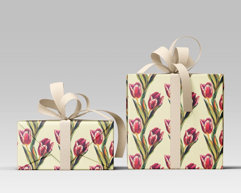 May include: Two gift boxes wrapped in floral patterned paper featuring red tulips with green leaves on a cream background. The boxes are tied with cream-colored ribbon and bows, creating a visually appealing presentation.