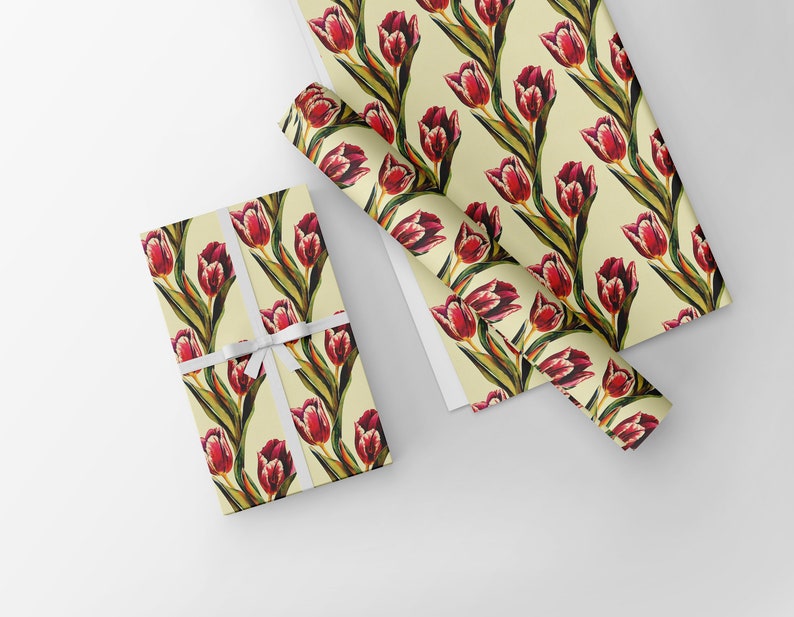 May include: Gift wrap featuring a repeating pattern of red tulips with green stems and leaves on a cream background. A wrapped gift tied with a white ribbon is shown next to rolls of the same wrapping paper.