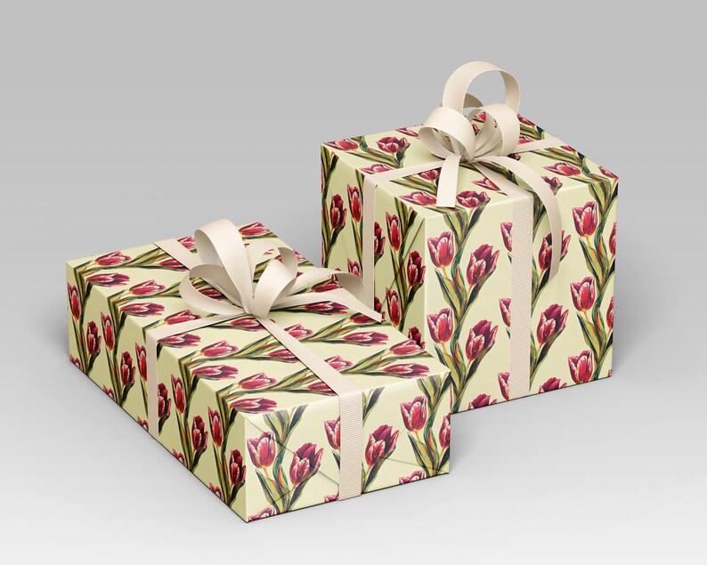 May include: Two gift boxes wrapped in floral patterned paper featuring red tulips on a cream background. Each box is tied with a cream-colored ribbon and bow, creating a classic and elegant presentation. The boxes are ideal for special occasions.