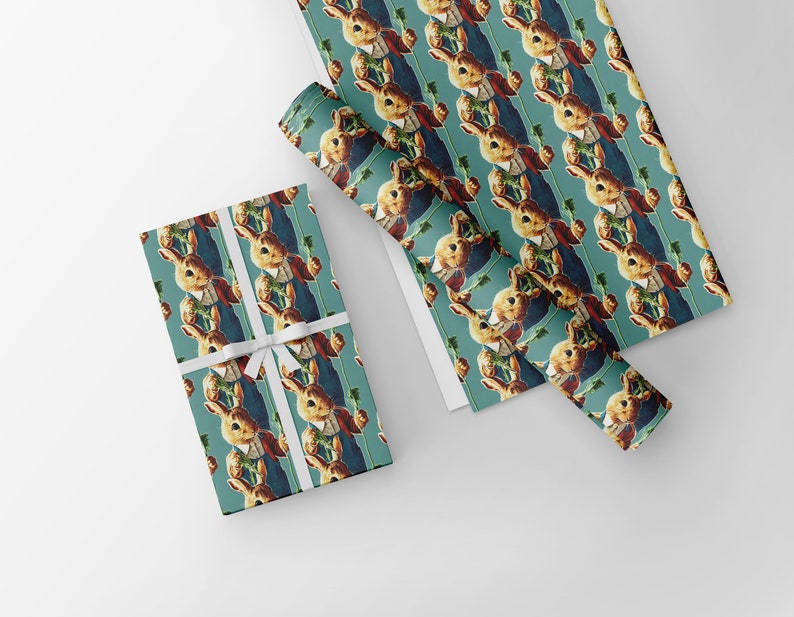 May include: Wrapping paper featuring a repeating pattern of a vintage illustration of a rabbit holding a carrot. The rabbit is dressed in a red jacket and blue vest. The paper is teal with a white ribbon tied around a wrapped gift.