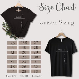 Puede incluir: Camisetas negras en perchas, mostrando una tabla de tallas para tallas unisex. La tabla enumera las tallas XS a 3X con medidas de ancho y largo en pulgadas. Tambi&eacute;n se ve el texto "Size Chart" y "Unisex Sizing".