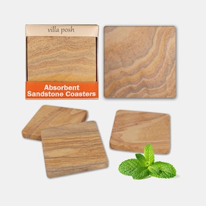 May include: Set of four absorbent sandstone coasters in a box with the text "Absorbent Sandstone Coasters" and "villa posh". The coasters are a light brown color with a natural stone pattern.