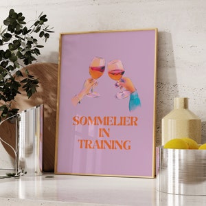 May include: A pink and purple poster with two glasses of red wine clinking together. The text "Sommelier in Training" is written in orange letters.