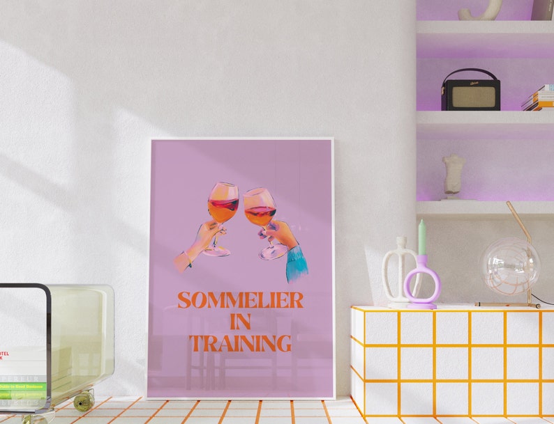 May include: A pink poster with two glasses of red wine clinking together. The text on the poster reads "Sommelier in Training".