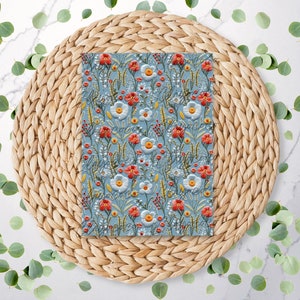 May include: A blue fabric with a floral pattern featuring white and red flowers. The fabric is on a woven straw placemat.