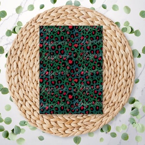 May include: A rectangular item with a green leopard print design, featuring black spots and red accents. The item is adorned with the word "Playococo" in a cursive font. The item rests on a woven, circular placemat.