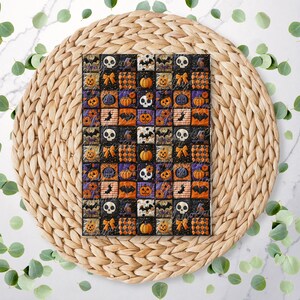 May include: A Halloween patchwork quilt with squares depicting pumpkins, bats, skulls, and bows in orange, black, purple, and white. The quilt is displayed on a woven, circular placemat, surrounded by green leaves. The design is festive and seasonal.