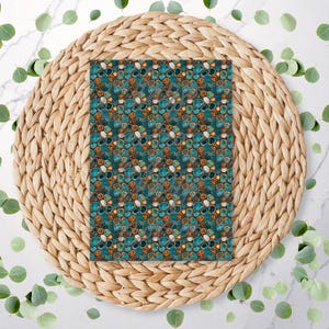 May include: A rectangular patterned surface with a teal, brown, and white design, resting on a woven, circular placemat. The pattern features an abstract design of rounded shapes. Green leaves are scattered around the placemat.
