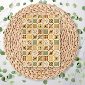 May include: A rectangular card featuring a repeating grid pattern of sunflowers, green squares, brown and yellow plaid squares, and cream-coloured squares with small floral motifs. The design uses a warm colour palette of yellow, green, and brown.