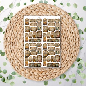 May include: A sheet of stickers featuring autumnal designs such as sunflowers, wellington boots, and teacups. The stickers display phrases like "A good mood is my favourite outfit" and are arranged on a white background, placed on a woven mat.