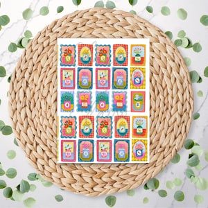 May include: A sheet of colourful stickers featuring various floral and botanical illustrations in decorative frames. The stickers showcase flowers, vases, and other plant-related imagery in a vibrant, artistic style. The sheet is set on a woven placemat with eucalyptus leaves.
