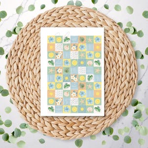 May include: A white gift bag with a repeating pattern of squares in pastel yellow, blue, and green. Each square contains a watercolor illustration of lemons, seashells, starfish, and tropical flowers. The bag is set on a woven placemat.