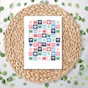 May include: A white card featuring a grid of colorful squares with beach-themed illustrations. The squares display images of crabs, seashells, palm trees, hibiscus flowers, and suns in shades of blue, pink, and green. The card is set on a woven placemat.