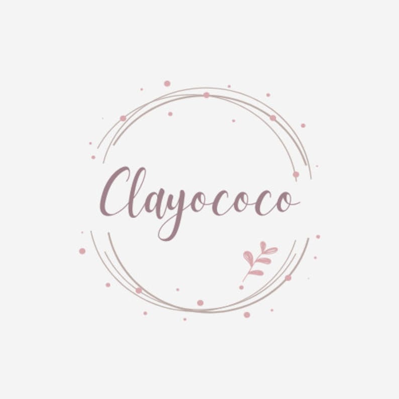 May include: A logo design featuring the word "Clayococo" in a cursive font, encircled by a delicate, hand-drawn style wreath. The design incorporates soft pink and taupe colors, with small dots and a sprig of leaves adding to the aesthetic.