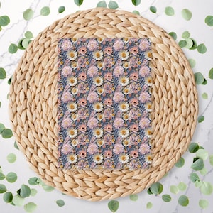 May include: A woven wicker placemat with a floral pattern fabric square in the centre. The fabric is a dark blue background with pink and white flowers.