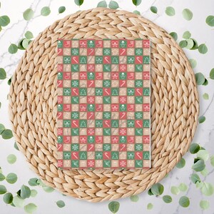 May include: A square Christmas pattern with red, green, and beige squares. Each square features a festive icon, including a Christmas tree, bow, candy cane, and snowflake. The pattern is displayed on a woven placemat with eucalyptus leaves.