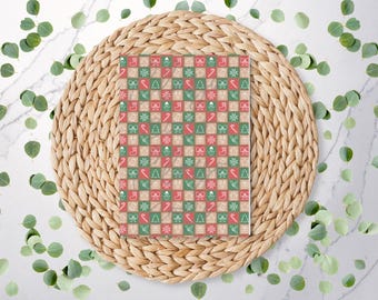 May include: A square Christmas-themed pattern with red, green, and beige squares. Each square contains a festive icon, including a Christmas tree, bow, candy cane, and snowflake. The pattern is displayed on a woven placemat with eucalyptus leaves.