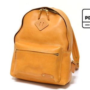 Puede incluir: Una mochila de cuero marrón con cierre de cremallera y un bolsillo frontal. La mochila tiene una cremallera y herrajes dorados.