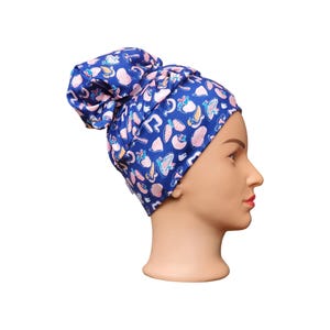 May include: A blue patterned surgical scrub hat with a pink and white design. The hat is tied on a mannequin head.