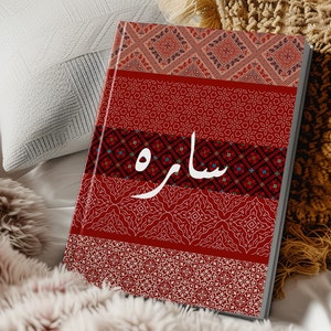 May include: A red and white patterned journal with the word "ساره" written in white on the cover.