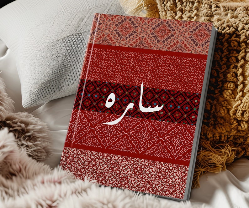 May include: A red and white patterned journal with the word "ساره" written in white on the cover.