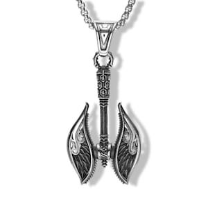 May include: A silver-toned metal pendant shaped like a double-bladed battle axe with intricate engravings and a textured handle, suspended from a matching silver-toned chain. The axe head features curved, wing-like blades with detailed patterns.