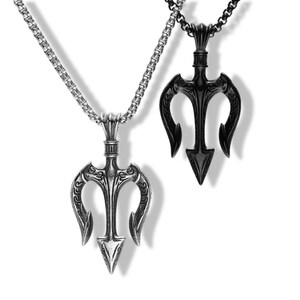 May include: Two trident pendants on chains. One pendant is polished silver-tone metal, and the other is matte black metal. Both feature intricate engraved detailing on the three prongs and a textured cylindrical connector at the top of the trident.