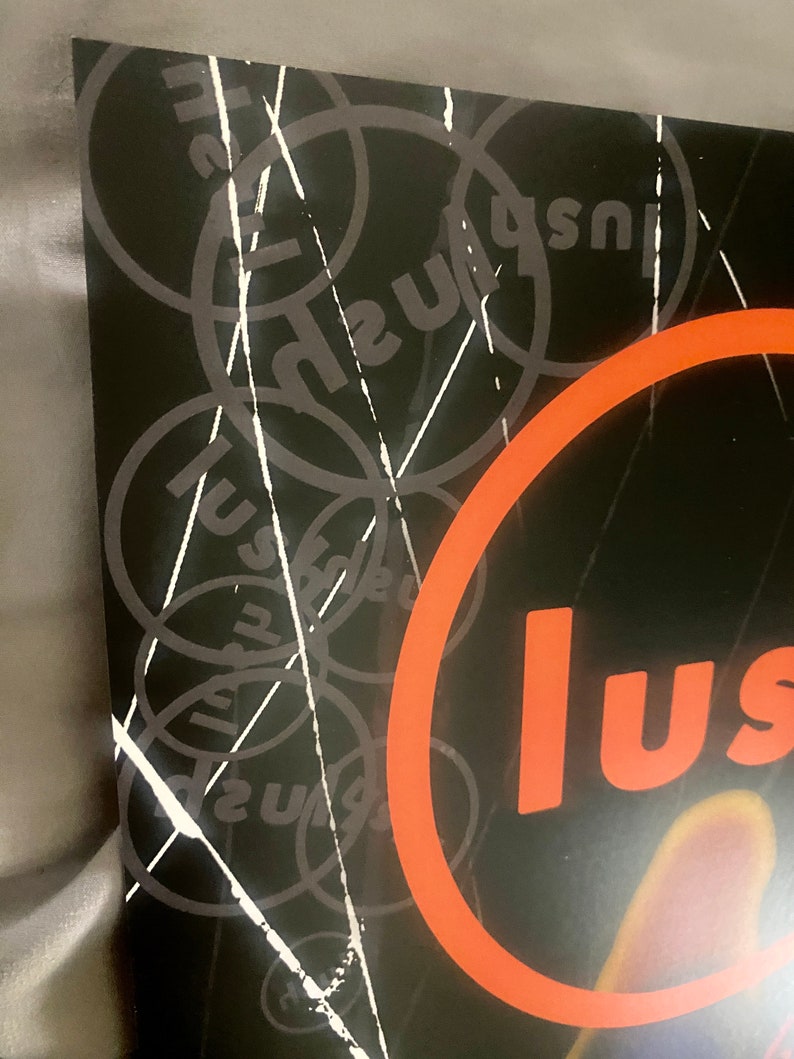 Pode incluir: Um gr&aacute;fico preto e branco com a palavra "lush" repetida em um padr&atilde;o circular. A palavra "lush" est&aacute; em um c&iacute;rculo grande de cor laranja.