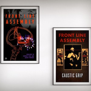 May include: Two framed posters with black frames. The left poster has the text "FRONT LINE ASSEMBLY" in red, with an orange and purple graphic on a black background. The right poster has the text "FRONT LINE ASSEMBLY" and "CAUSTIC GRIP" in red on a dark brown background.