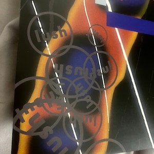 Pode incluir: Um cartaz preto e branco com um design abstrato colorido. O cartaz apresenta a palavra "lush" repetida em um padr&atilde;o circular. O cartaz tamb&eacute;m inclui a palavra "Spook" em uma fonte estilizada.