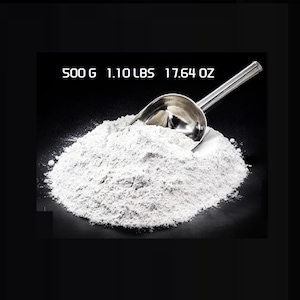 May include: A pile of white powder with a silver scoop on a black background. Text at the top reads: 500 G 1.10 LBS 17.64 OZ.