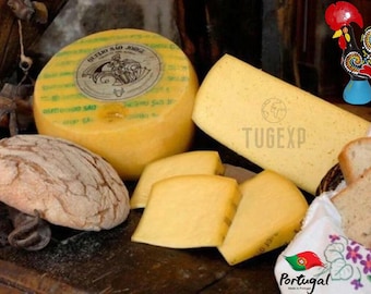 May include: A still life featuring a wheel of yellow cheese with a label, a loaf of bread, and sliced cheese. A decorative rooster figurine and a basket of bread slices are also present. The image has a rustic, inviting feel.