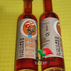 May include: Two glass bottles of red chili oil with a rooster logo and the text "Gota Gota Palato Enche de Picante Piri Piri Audaz com azeite" on the label. The bottles are 50 ml each.