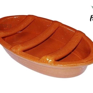 May include: A terracotta oval-shaped dish with three ridges on the inside. The dish is made in Portugal and is perfect for serving food.