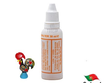 May include: A white plastic bottle with an orange label that reads "OFILTER 30 ml e" and "TUGEXP". The label also includes instructions for use and storage in Portuguese. The bottle is sitting on a white surface.
