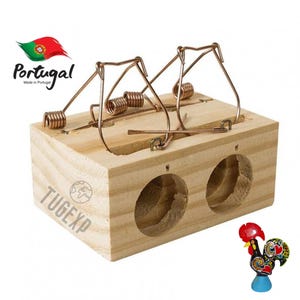 Puede incluir: Una trampa para ratones doble de madera con dos jaulas de resorte. La trampa está hecha en Portugal y tiene el texto "TUGEXP" impreso en el lateral. Una pequeña figura de gallo colorida se encuentra en la esquina inferior derecha de la imagen.