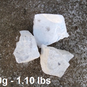 May include: Three white, irregularly shaped chunks of chalk on a gray concrete surface. 500g - 1.10 lbs.