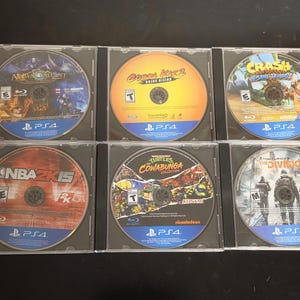 Op de afbeelding: Zes PlayStation 4-speldiscs in doorzichtige plastic hoesjes. De titels zijn All-Star Fruit Racing, Cobra Kai 2: Dojos Rising, Crash Bandicoot N. Sane Trilogy, NBA 2K15, Teenage Mutant Ninja Turtles: The Cowabunga Collection en Tom Clancy's The Division.