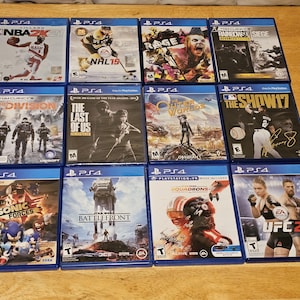 Könnte beinhalten: Eine Sammlung von 12 Videospiel-Hüllen für die Playstation 4 Konsole. Die Hüllen sind in drei Reihen mit jeweils vier Hüllen angeordnet. Die Spiele beinhalten NBA 2K21, NHL 19, Rage 2, Tom Clancy's The Division, The Last of Us Remastered, Outer Worlds, The Show 17, Sonic Forces, Star Wars Battlefront, Star Wars Squadrons und UFC 2.
