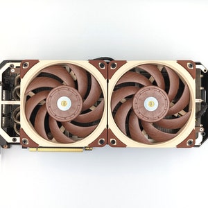 May include: A beige and black graphics card with two large brown fans. The fans have a wood-like texture and a white center.