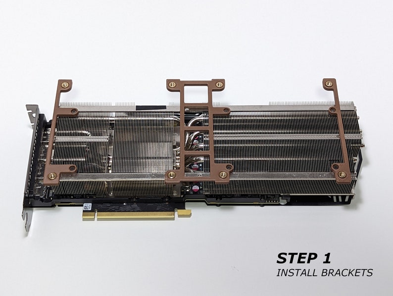 Puede incluir: Primer plano de una tarjeta gr&aacute;fica con un gran disipador de calor y tres soportes met&aacute;licos. Los soportes est&aacute;n etiquetados como "STEP 1 INSTALL BRACKETS".