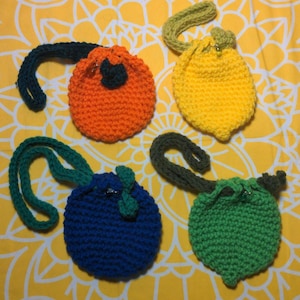 May include: Four crocheted drawstring bags in different colors: orange, yellow, blue, and green. Each bag has a crocheted strap.