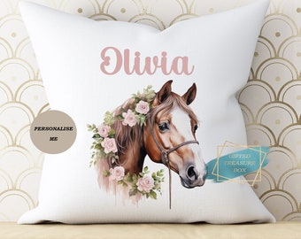 May include: White pillow with a brown horse with a pink floral crown and the name Olivia printed in pink. The pillow has a personalized me label and a gifted treasure box logo.