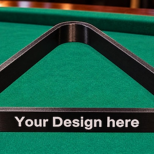 May include: A black triangular billiard ball rack with a textured surface. The front side of the rack features the white text "Your Design here" printed in a clean, sans-serif font. The rack is designed to hold standard billiard balls for play.