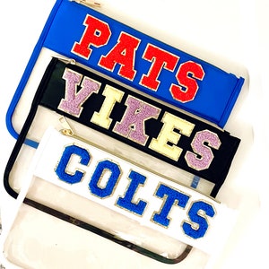 May include: Three clear zippered pouches with different colored backgrounds and team names in colorful embroidered letters. The top pouch is blue with "PATS" in red letters. The middle pouch is black with "VIKES" in yellow and purple letters. The bottom pouch is white with "COLTS" in blue letters.